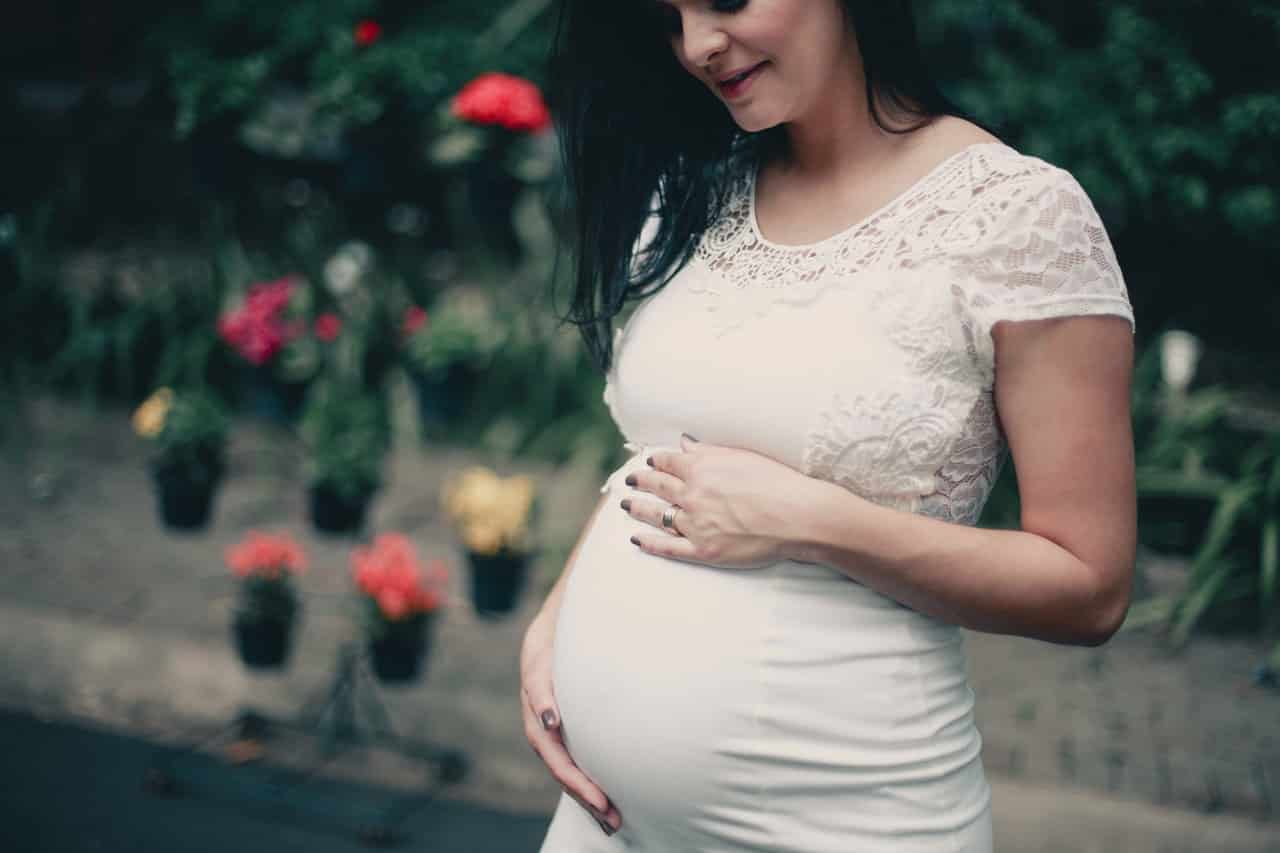 תמונה של אישה בהריון מסתכלת למטה על הבטן שלה ומחייכת