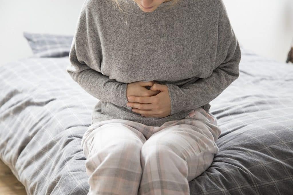 אישה עם וירוס בבטן יושבת על המיטה