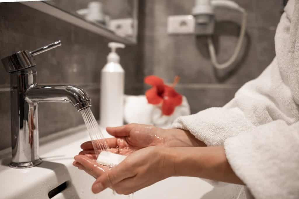 אישה עם חלוק לבן וסבון קשה בידיים