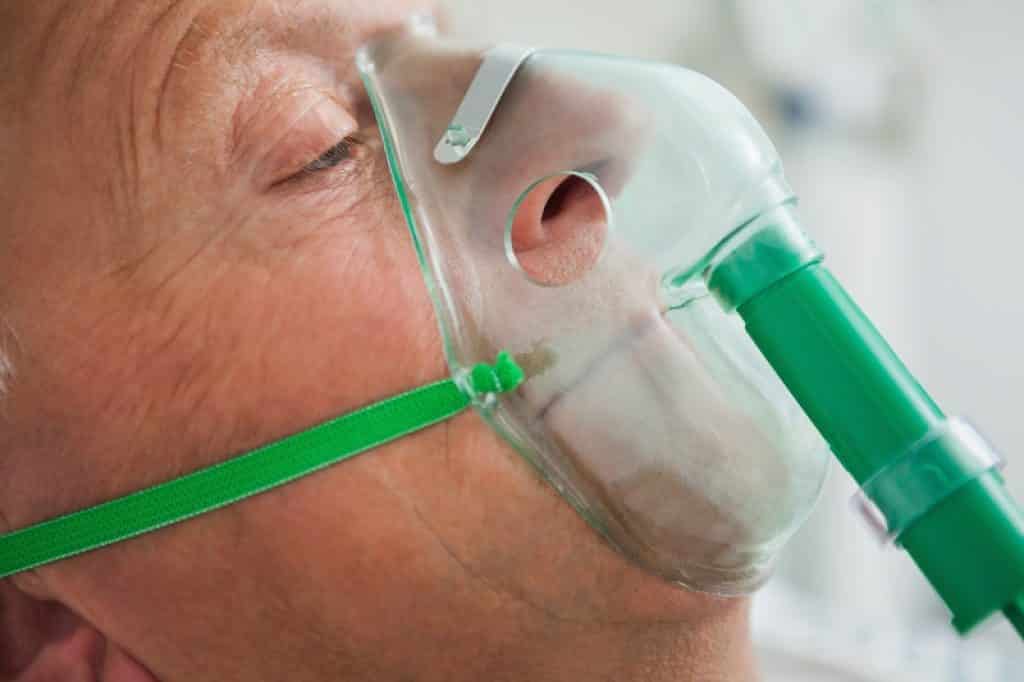 איש מבוגר שמתקשה לנשום מקבל חמצן להקלה