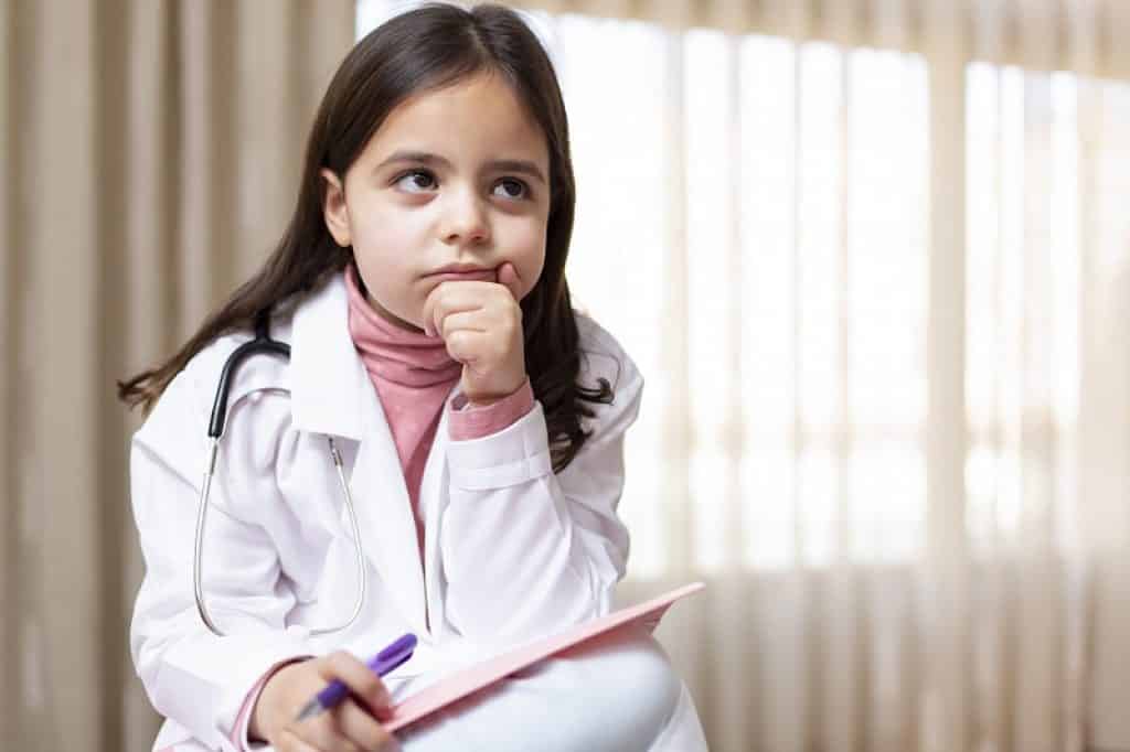 ילדה בחלוק רופאה מחזיקה את הפנים במבט של שאלה