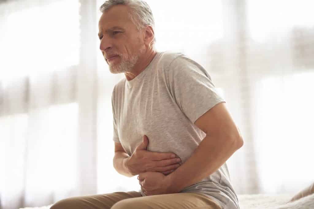 איש מבוגר סובל מתופעות של וירוס בבטן