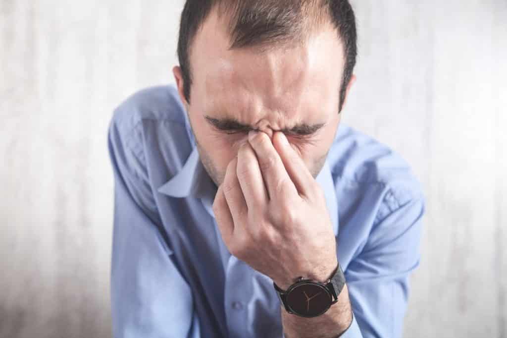 איש עם סינוסיטיס סובל מכאבים באף