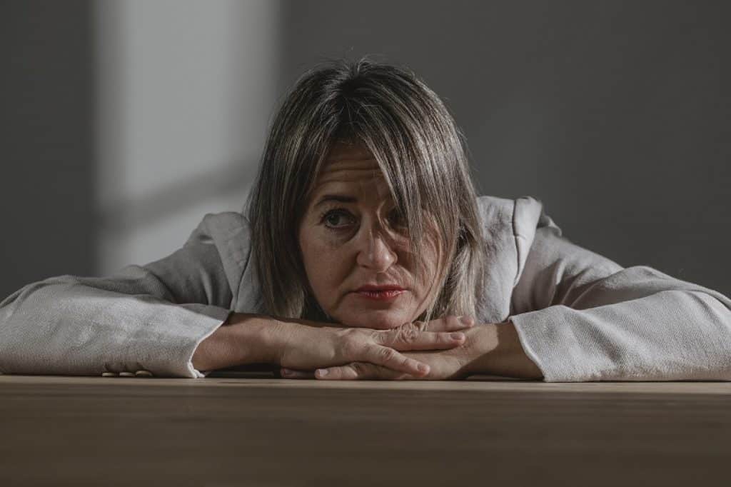 אישה עם גקט אפור נשענת על שתי הידיים הקדמיות בחשש