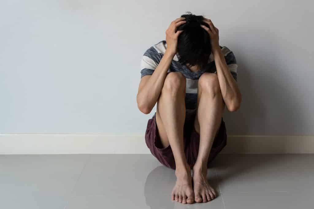 איש צעיר יושב מכונס סובל מדיכאון